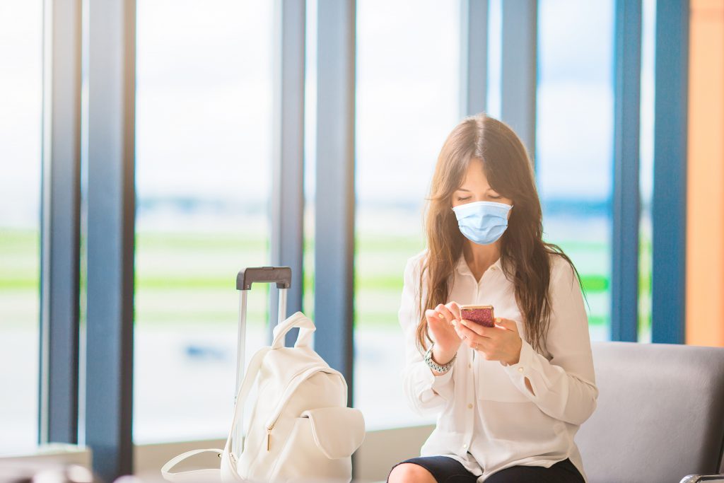 Young tourist woman using cell phone at airport while traveling. 