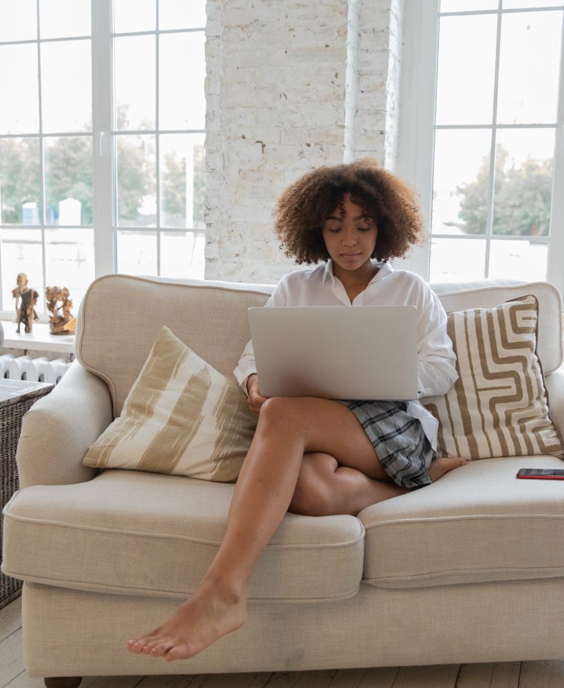 Girl sitting on couch typing on her computer.